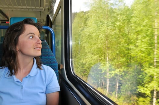 Young woman passanger sitting inside train and looking trough window