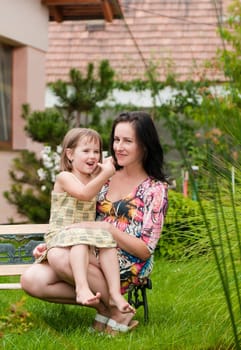 Mother and daughter spending time together in garden - family house in background