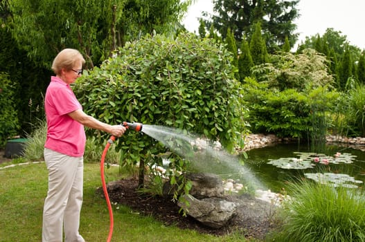 Senior woman watering garden