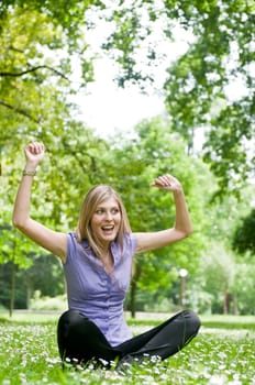 Young happy woman siting in grass with flowers enjoying life