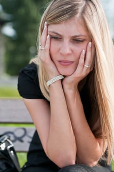 Young worried beautiful woman siting on bench - head in hands