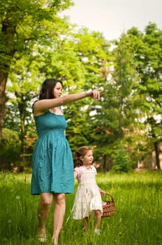 Mother shows with finger to her cute little daughter something interesting in distance