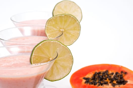 Three lime slices in a cocktail glass each and a papaya fruit