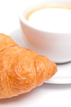 A close-up of a Crossiant and a cup of cappuccino