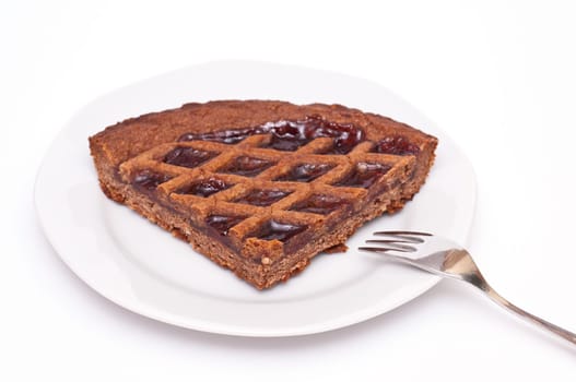 A plate with a kitchen cable and a Linzer cake in front of a white background