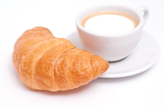 A cup of cappuccino and a croissant against a white background