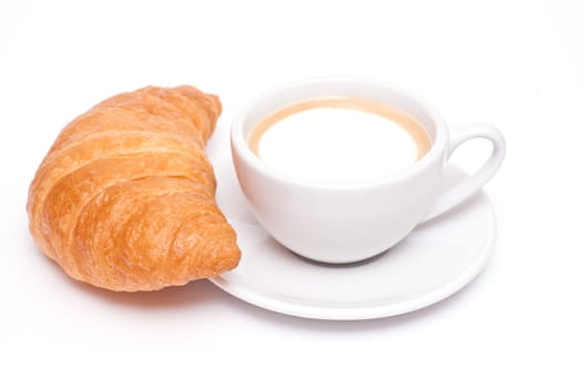 A croissant and a cup of cappuccino against a white background