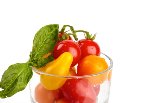A jar filled with colorful fresh small organic tomatoes against a white background
