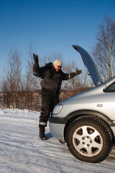 In cold winter day sad man looking at his broken car