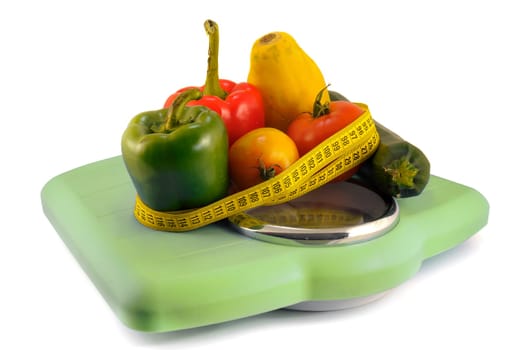 Fruits and vegetables in a weight scale with measuring tape isolate in white