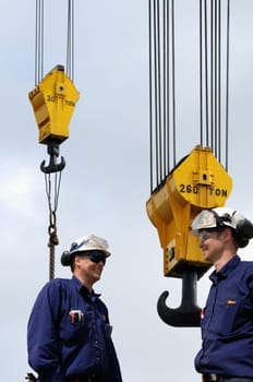 two building-workers with large mobile crane in background
