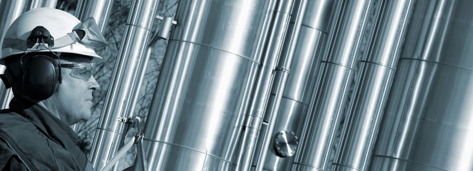oil and gas worker, engineer, close-ups, large shiney gas pipes in background, panoramic view