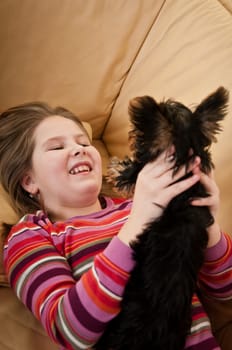 Portrait of cute happy child (girl) playing with little dog