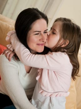 Child (cute ligirl) kissing her mother - indoors at home