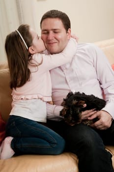 Child (cute ligirl) kissing her father - indoors at home