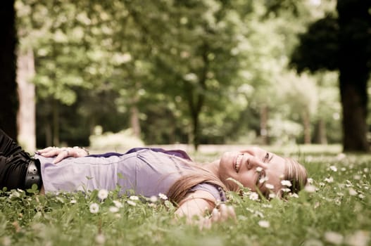Detail of young woman lying in fresh green grass with flowers - low angle view