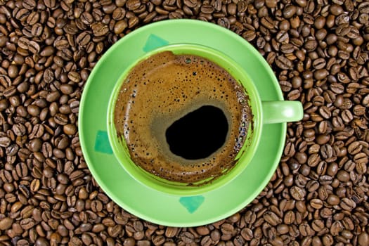 brown roasted coffee beans and green cup