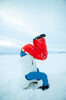 Woman doing yoga and a headstand in snow on a white winter day
