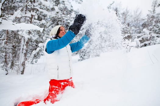 Woman throwing snow up in the air on a white, cold winter day