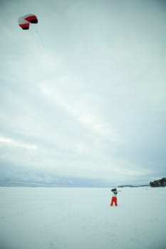 Woman flying a kite on frozen sea shore on a winter day