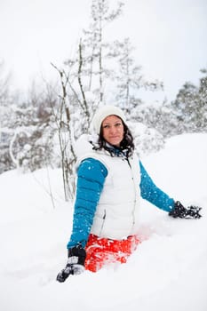 Woman sitting and playing in snow on a white winter day