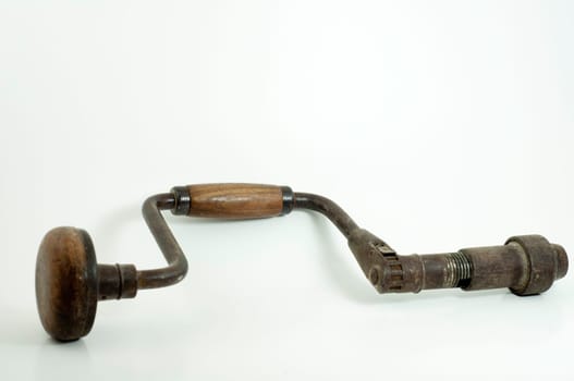 antique hand drill with wooden handles and crank on white background