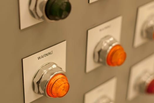 bright orange warning light on electrical panel shallow depth of field