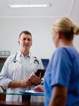 Doctor talking to young woman at work as nurse in medical clinic and taking medical file.