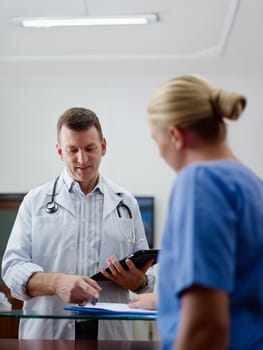 Doctor talking to young woman at work as nurse in medical clinic and taking medical file.