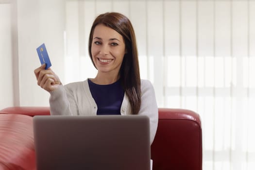 E-commerce with happy woman using pc and credit card while shopping on the web at home