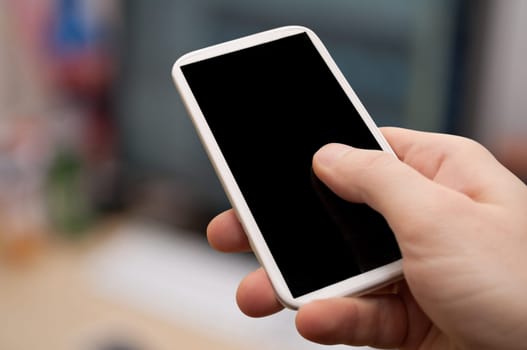 Closeup of Man&#039 s Hand Touching Screen of Smartphone in Office