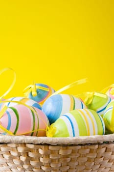punnet with colorful easter eggs on yellow background