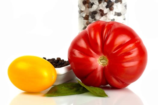 Two fresh organic tomatoes with salt and pepper mill against white background