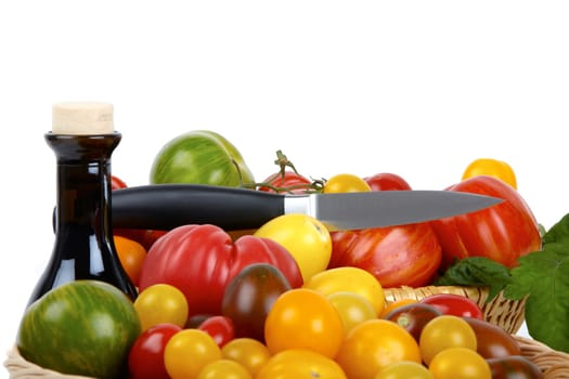 Numerous biotomets in basket with knife and balsamic vinegar against white background