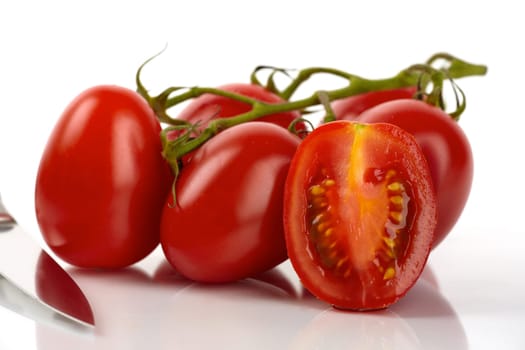 Fresh Roma tomatoes with knife against white background