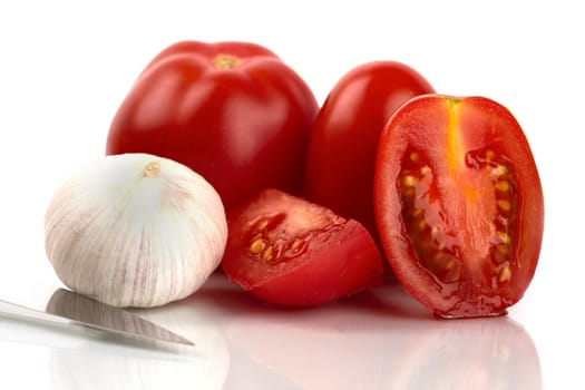 Fresh tomatoes with knife and garlic onion against white background