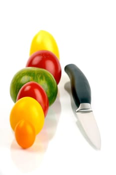 Various organic tomatoes in a row with a knife