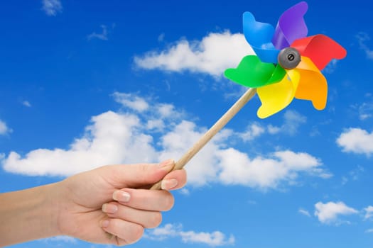 Hand holding pinwheel over a sky background