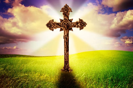 Beautiful image of a cross in a grass field with a holy cloudy sky
