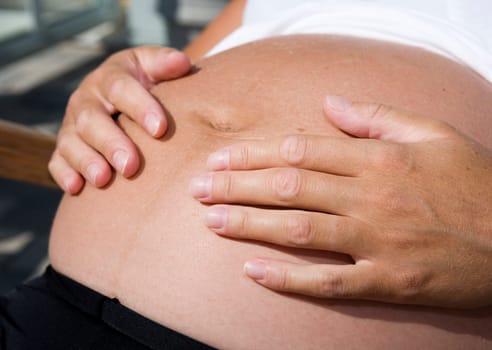 Pregnant woman holding her hands on the stomach