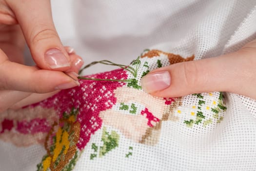 Woman hands doing cross-stitch. A close up of  embroidery.