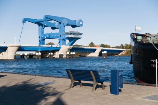 Bascule bridge near Anklam with harbour,bench and ship's bow in the foreground in bright weather and blue skies