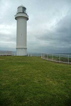 white lighthouse, dark grey sky, almost raining, coastline near sydney