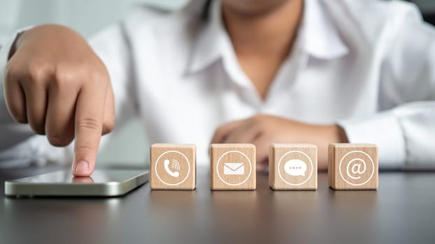 Businesswoman pointing finger at phone screen with communication icons for support or providing services and consulting to customers.