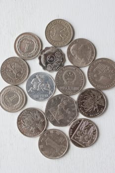 Assorted white coins from different countries on a white background, top view.