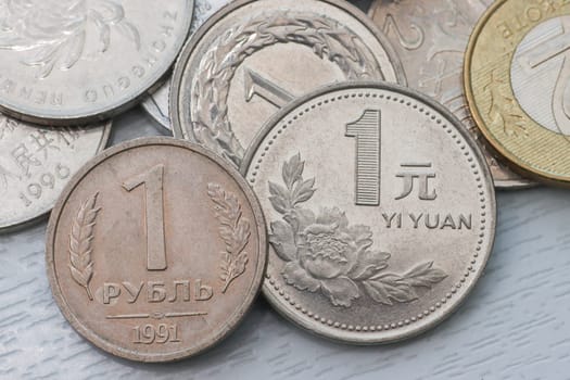 Top view of coins - one Russian ruble, and other different Chinese yuan. Scratched coin.