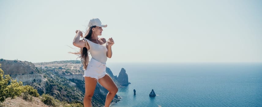 Woman travel sea. Young Happy woman in a long red dress posing on a beach near the sea on background of volcanic rocks, like in Iceland, sharing travel adventure journey