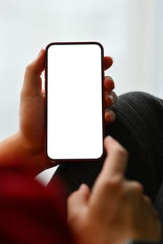 Close up man hands holding smartphone with white screen while relaxing on couch.