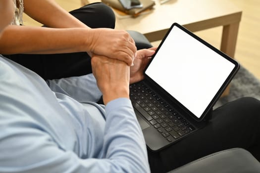 Close up view of a senior couple holding hands and watching something on digital tablet.