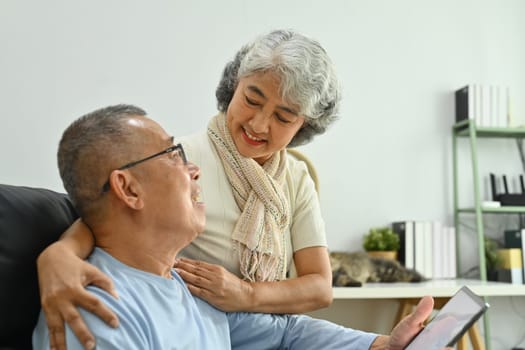 Lovely senior couple talking and watching video on digital tablet together. Elderly and technology concept.